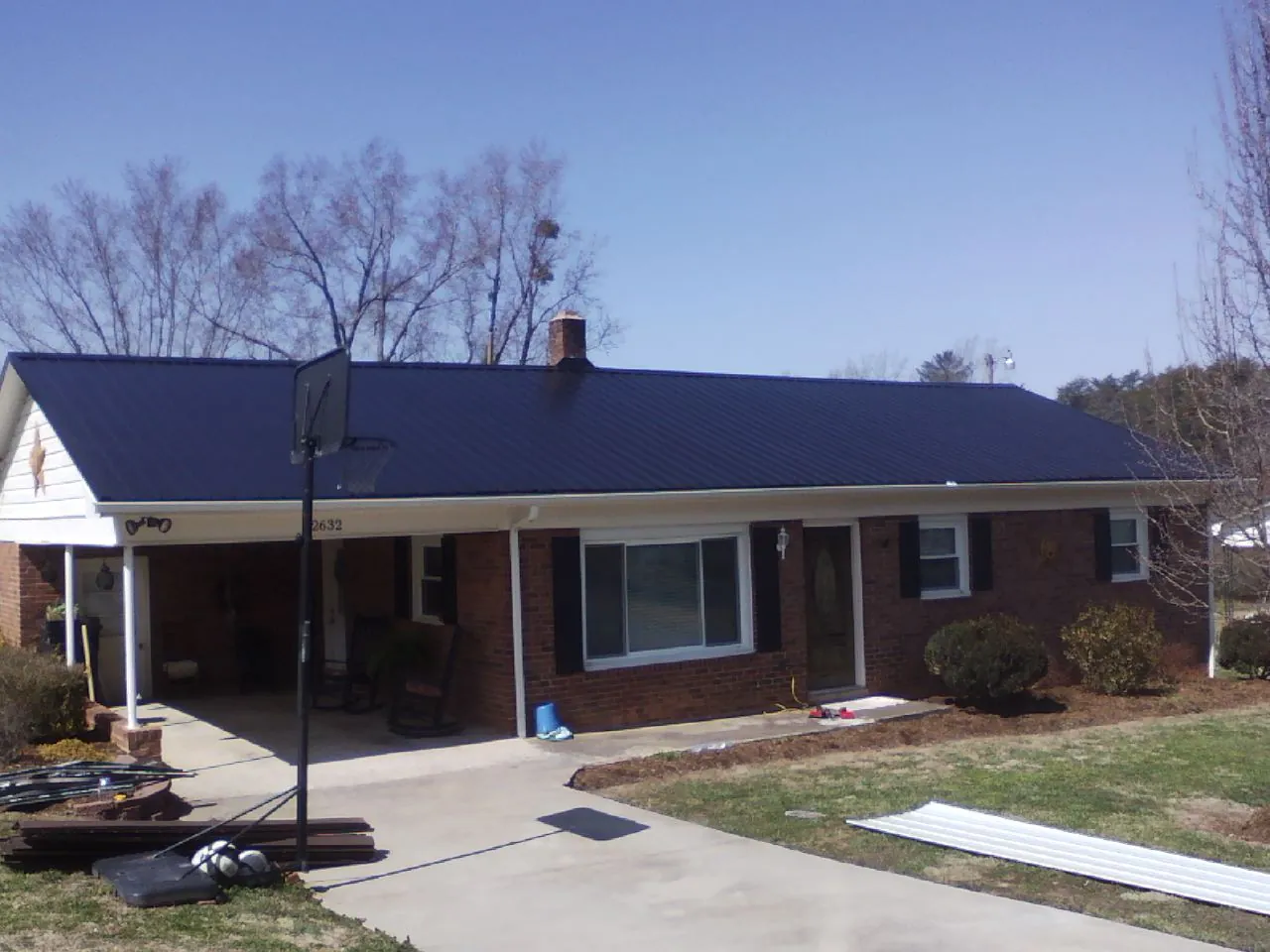 Finished dark blue metal roof on a brick ranch with a carport in Mount Clare
