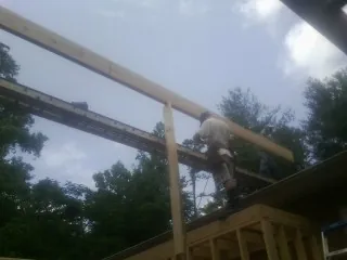 Carpenter setting a ridge beam over a new addition frame — Ice Dam Removal by Roofing Brothers in Mount Clare