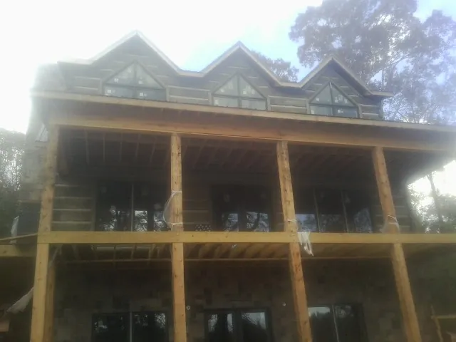 Dormers and porch framing on a large log home under construction — Roof Coating work by our crew in Mount Clare