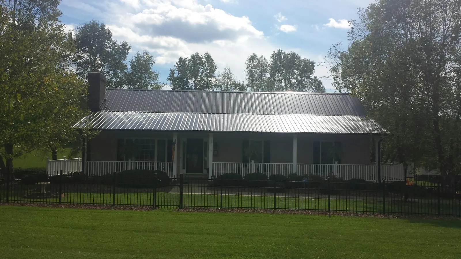 Gray metal roof on a brick ranch with a full width front porch — Gutter Guard Installation work by our crew in Mount Clare