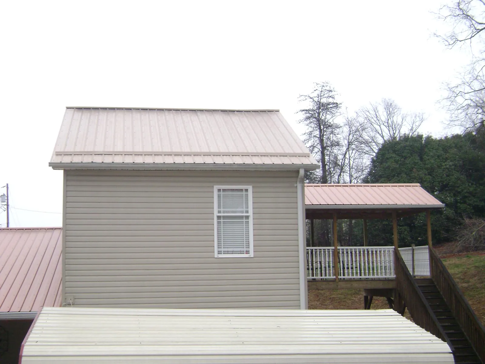 Tan metal roofs on a two story addition and attached porch, from a Roof Replacement job in Mount Clare